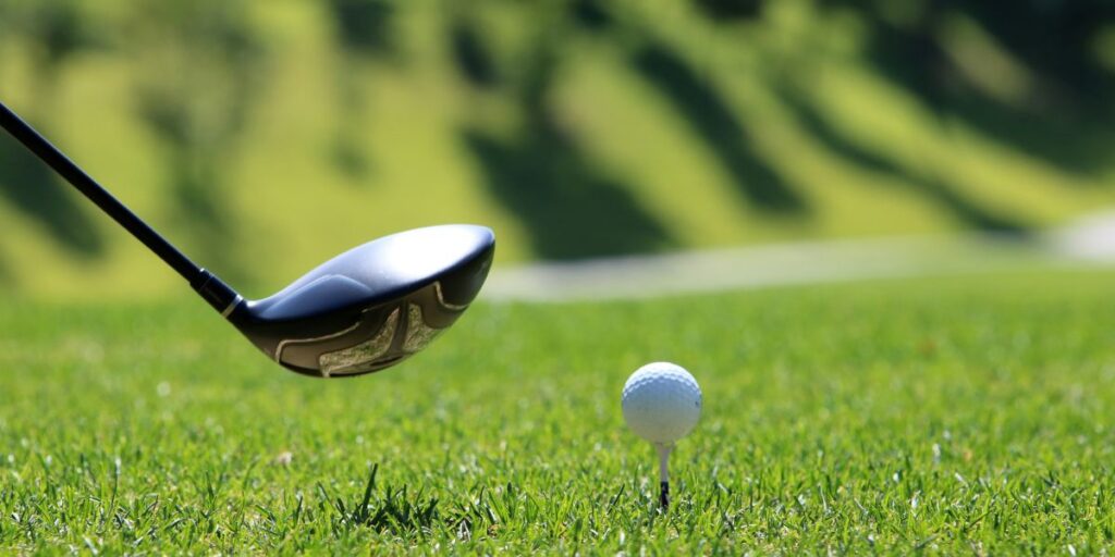 driver hovering in the air before hitting a golf ball on a tee peg