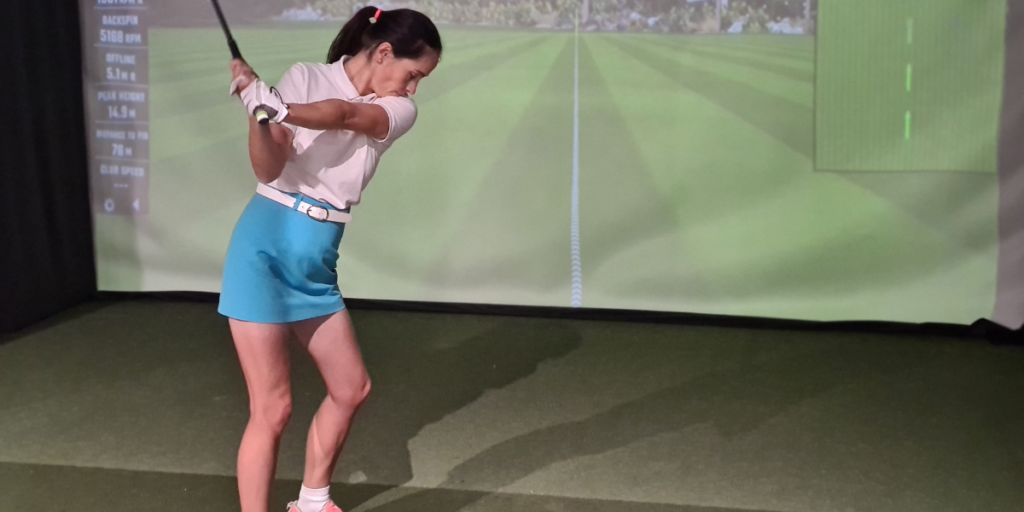 golfer using a golf simulator about to hit a golf ball