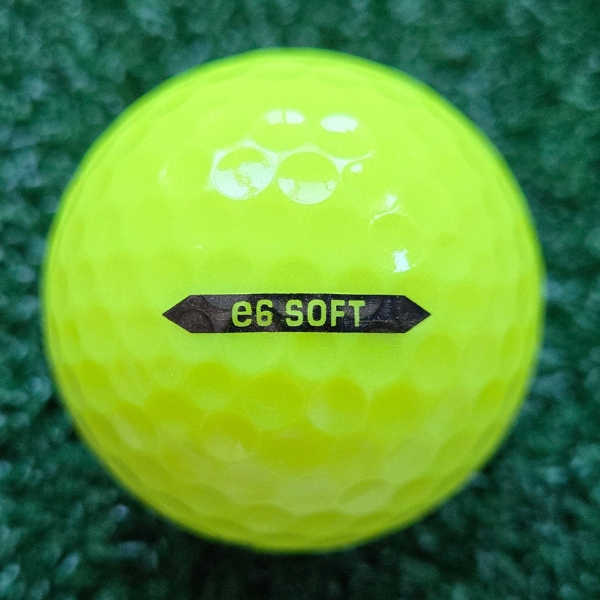 2025 Bridgestone e6 Soft Optic Yellow Golf Ball showing the alignment arrow that says "e6 Soft" on a black line with pointy ends on each side